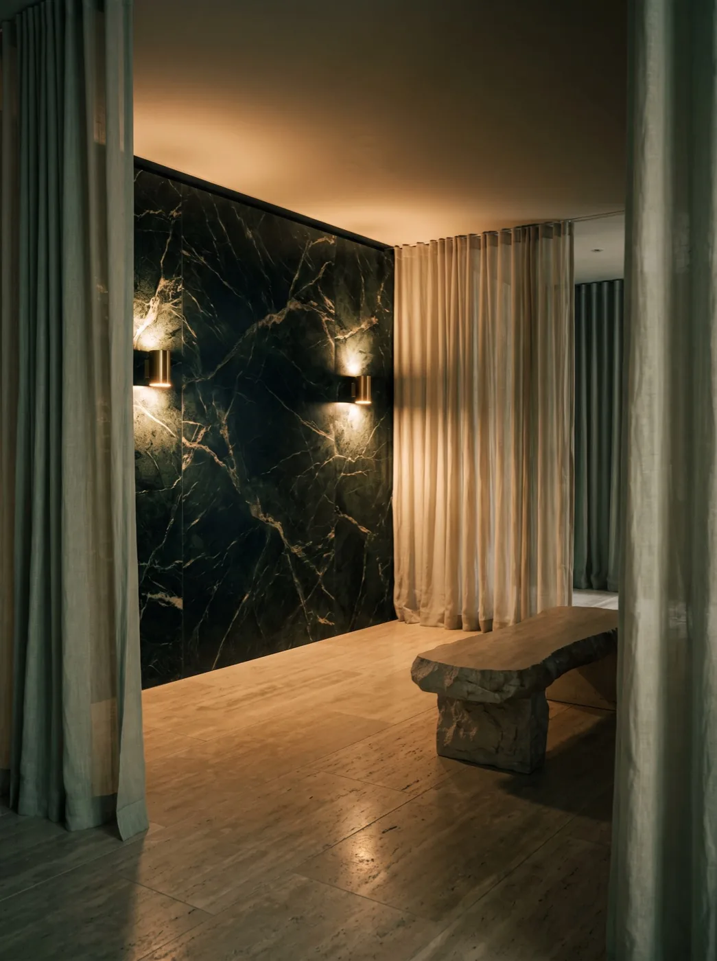 The West Hollywood studio: forest-green marble feature wall, brass sconces, travertine floor